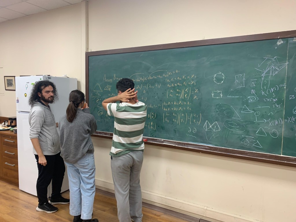 Students and researchers working together at a blackboard during an ISTRINGY session