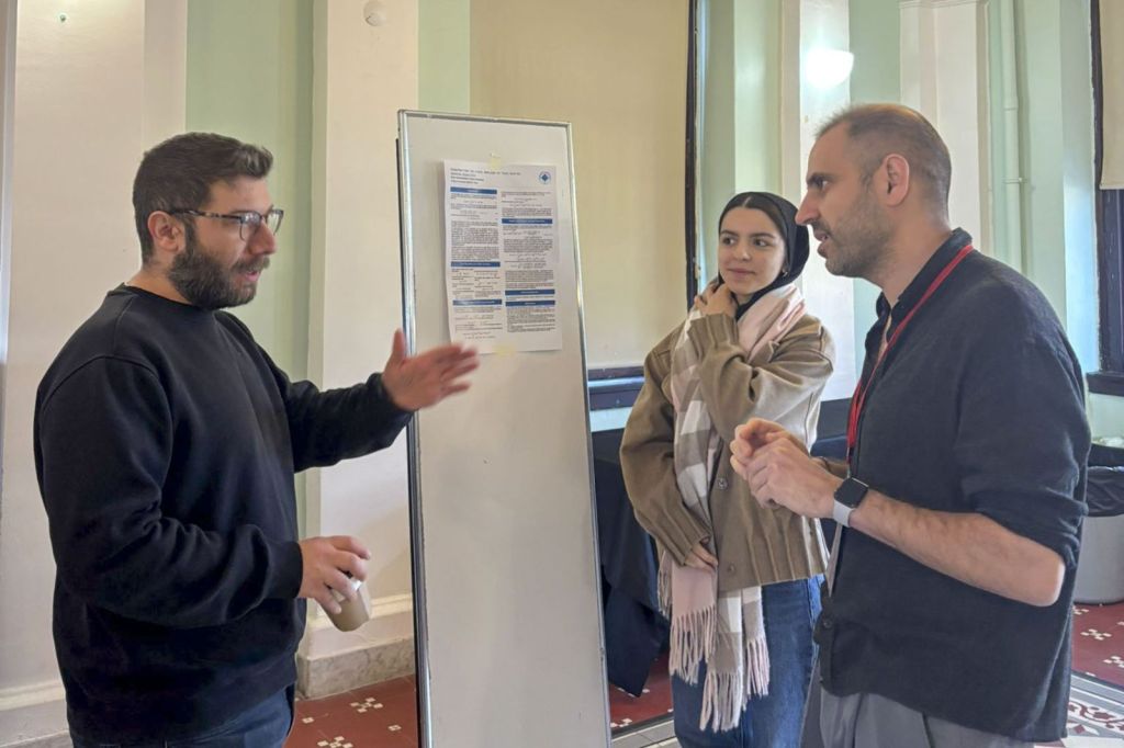 Researchers discussing a poster during an ISTRINGY meeting in Istanbul